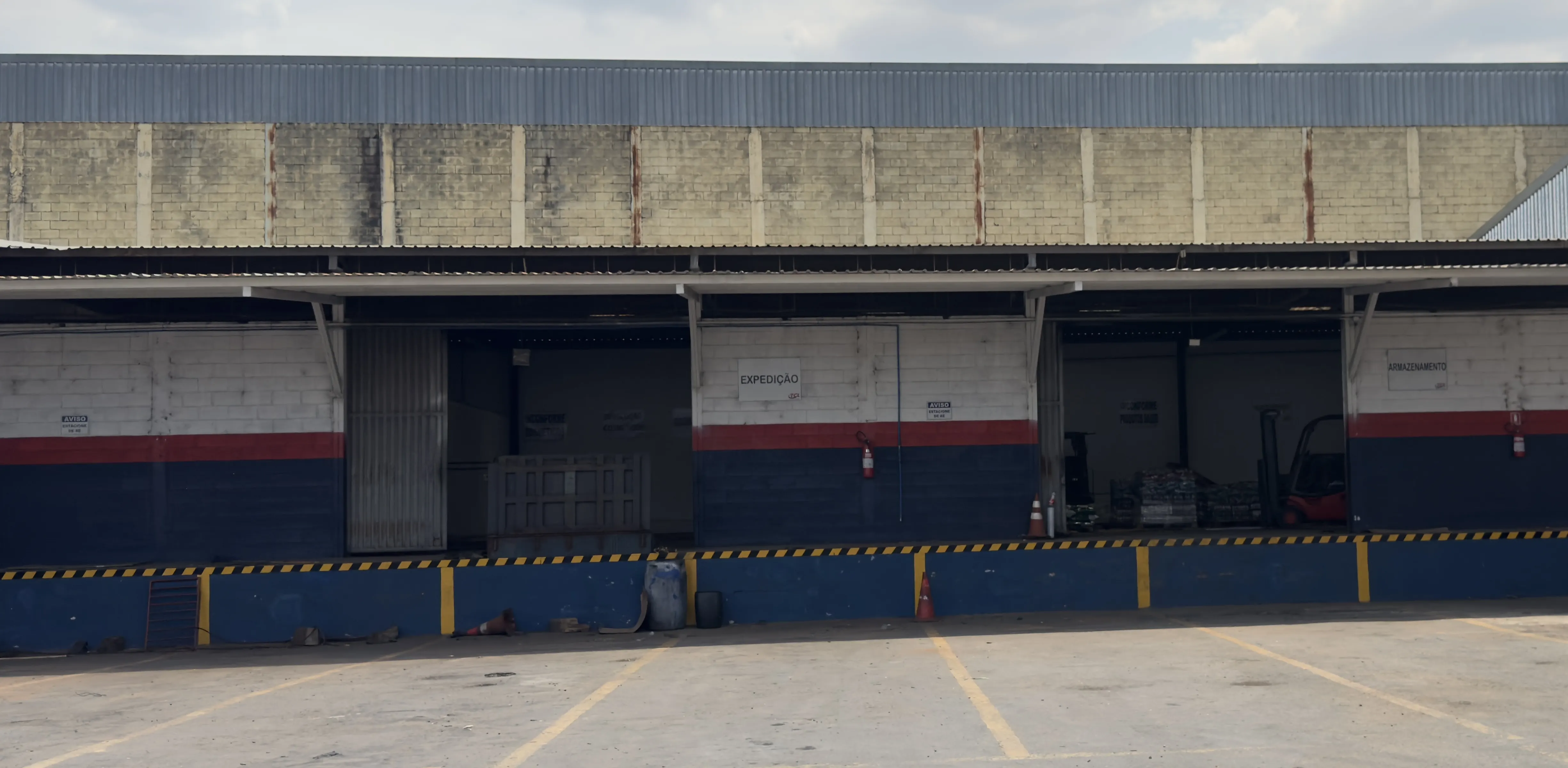 Docas do galpão da TCL, com áreas de expedição e armazenagem e uma empilhadeira no interior.